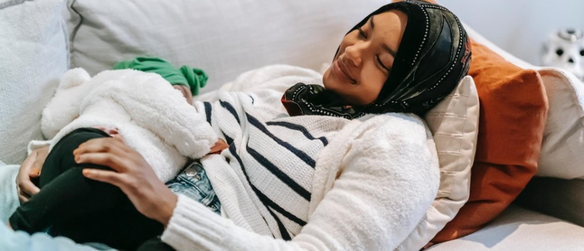 Woman laying on sofa with breastfeeding baby