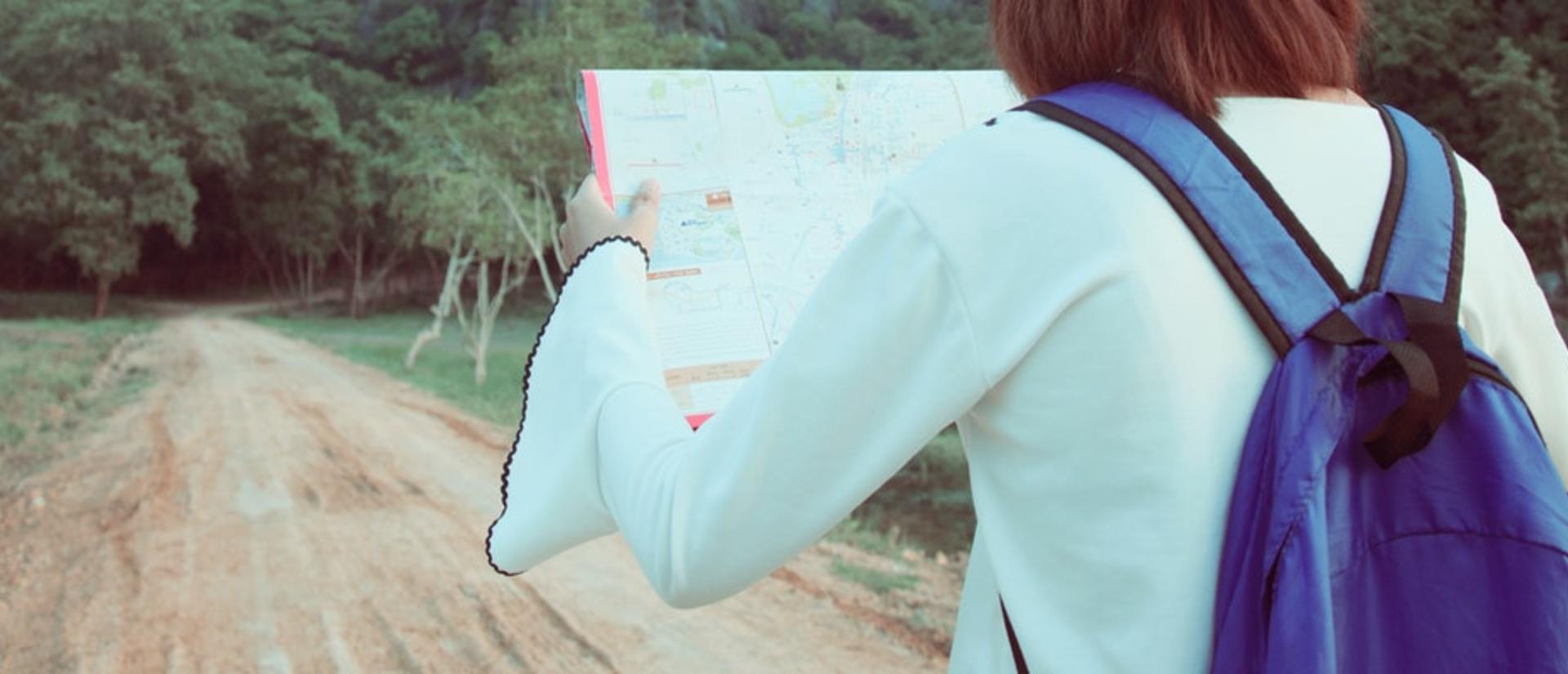 Woman holding a map in front of green mountains