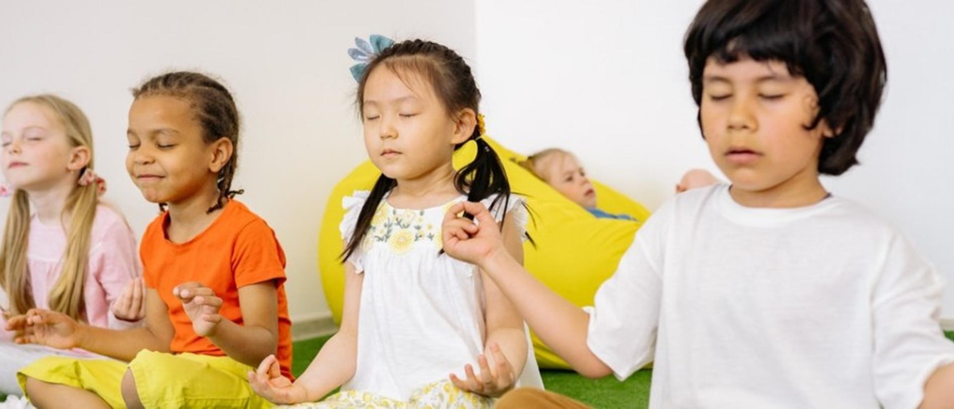 Children sitting in criss cross position with closed eyes.